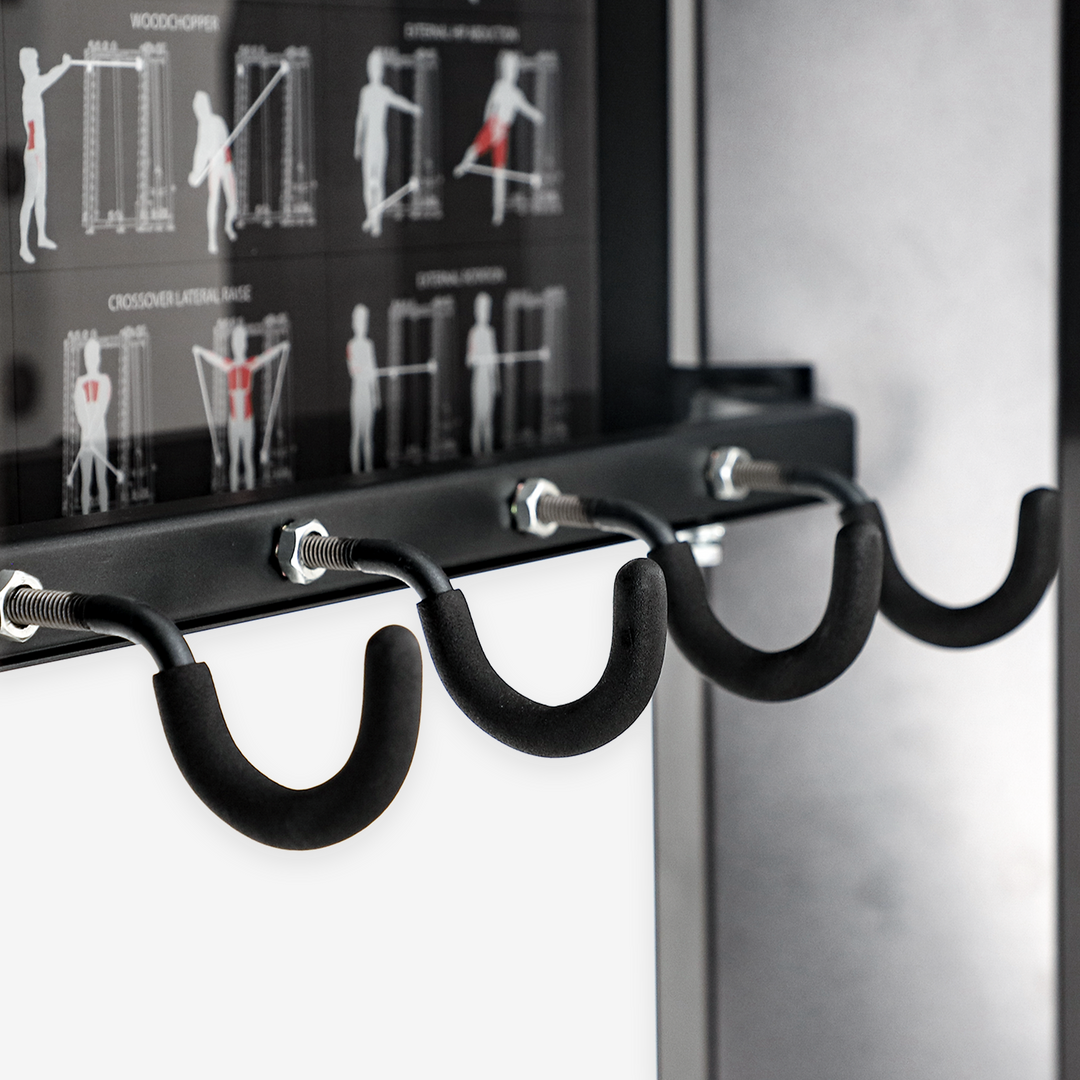 Black exercise bar with hooks on a white wall, next to a chart showing exercise illustrations.
