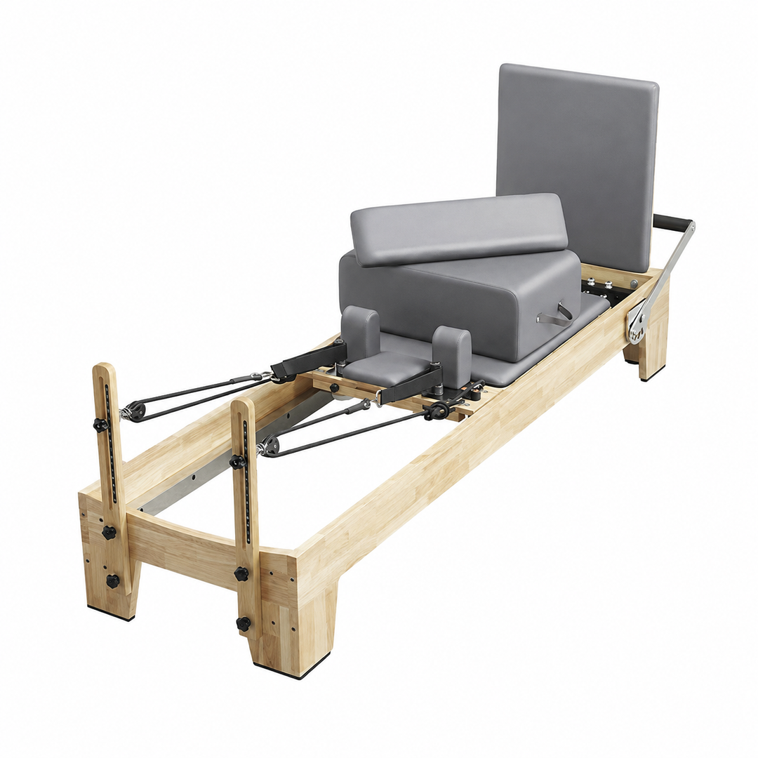 A wooden Pilates reformer machine with gray padded seat, backrest, and footrest, shown on a plain white background.